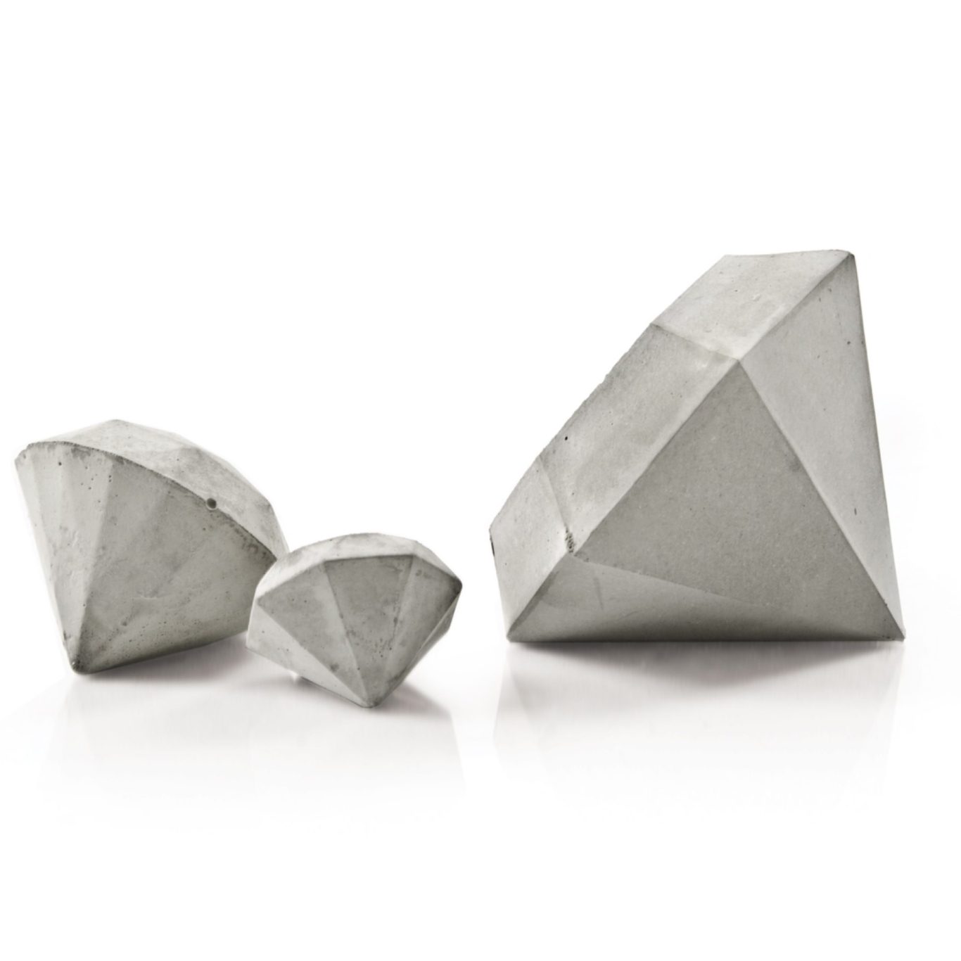 Diamant Skulpturen aus Beton zur Dekoration, Ringhalter oder Briefbeschwerer von Pasinga Props Drei geometrische Diamant Formen aus hellem Beton in verschiedenen Größen, dreieckig und kantig auf hellem Hintergrund.