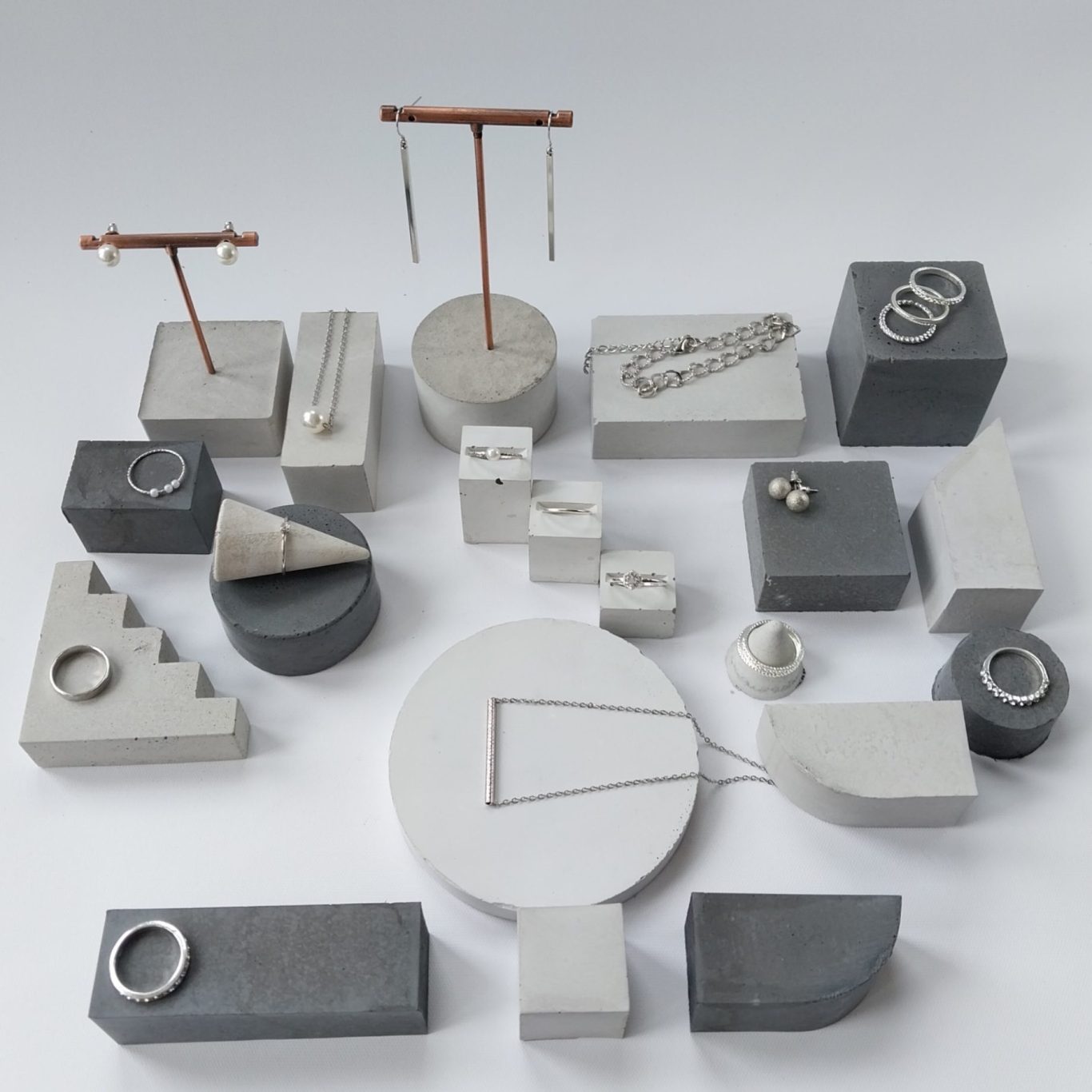 Geometrische Schmuckständer aus hellem und dunklem Beton von Pasinga Props Verschiedene geometrische Objekte aus Beton in unterschiedlichen Formen und Größen angeordnet zur Schmuckpräsentation